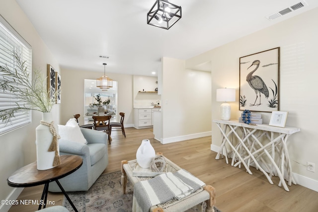 living area featuring baseboards, visible vents, and light wood-type flooring