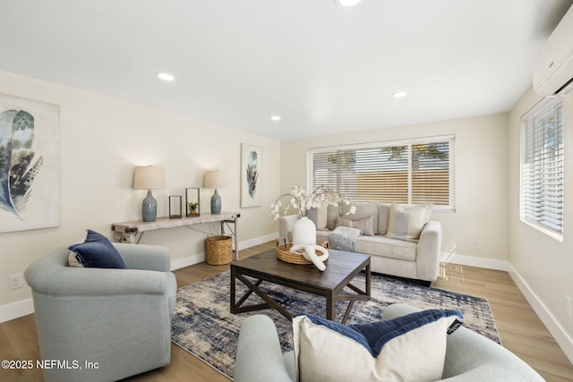 living area featuring a wall unit AC, light wood-style flooring, recessed lighting, and baseboards