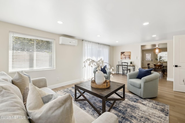 living area with an AC wall unit, recessed lighting, light wood-type flooring, and baseboards