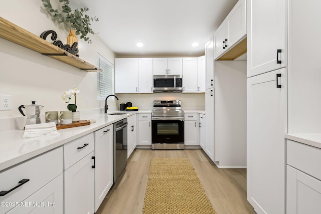 kitchen featuring a sink, light countertops, appliances with stainless steel finishes, white cabinets, and open shelves