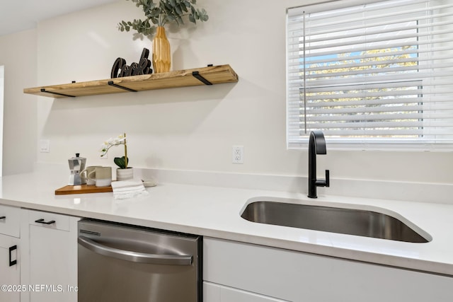 kitchen with white cabinets, dishwasher, light countertops, and a sink