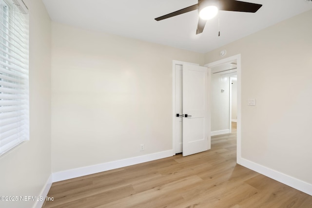 unfurnished bedroom with baseboards, attic access, and light wood finished floors