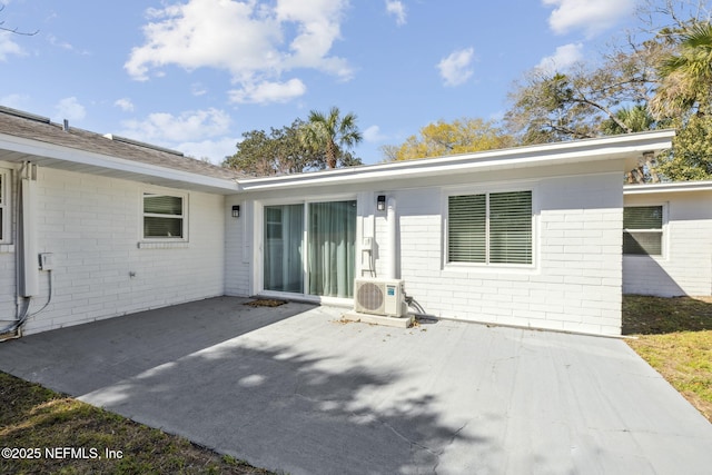 back of property with brick siding, a patio, and ac unit