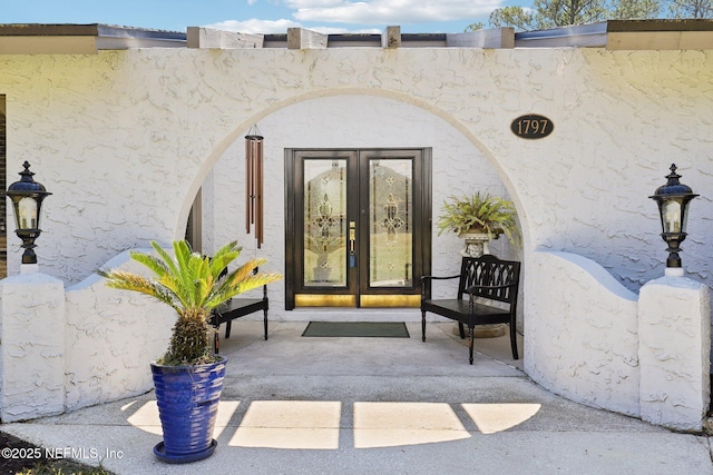 doorway to property featuring stucco siding and french doors