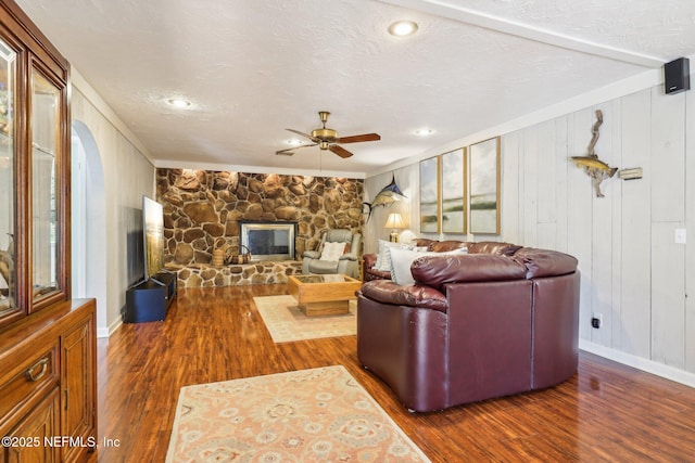 living room with a ceiling fan, wood finished floors, a fireplace, and a textured ceiling