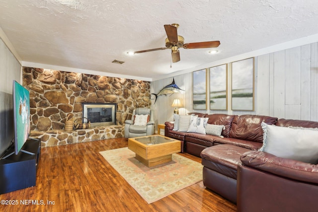 living room with visible vents, a fireplace, a textured ceiling, and wood finished floors