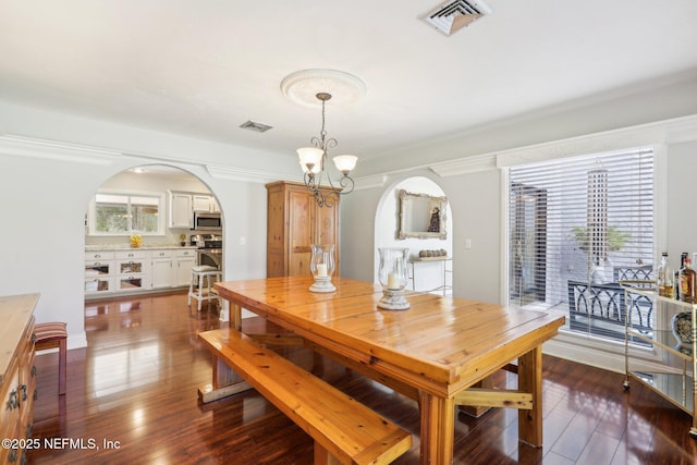 dining room with arched walkways, visible vents, a healthy amount of sunlight, and dark wood-type flooring