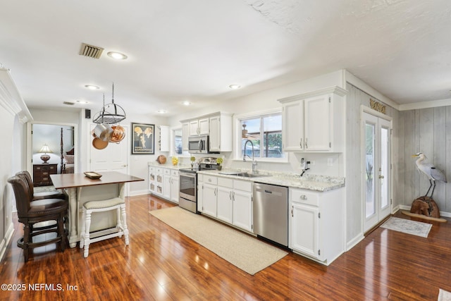 kitchen with visible vents, dark wood finished floors, a sink, white cabinets, and appliances with stainless steel finishes