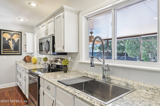 kitchen with dark wood-style floors, baseboards, a sink, stainless steel appliances, and white cabinetry