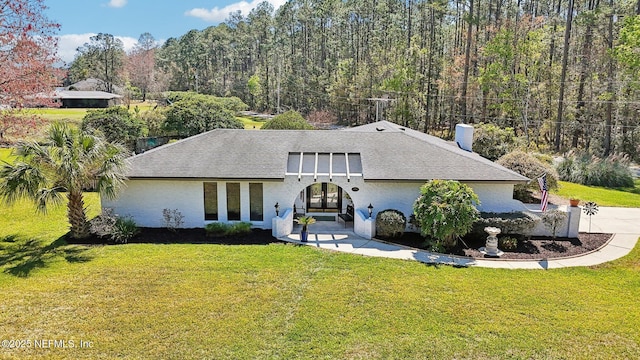 mid-century modern home featuring french doors, a front yard, and roof with shingles