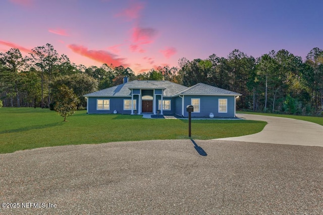 view of front of property featuring driveway, a chimney, and a front yard