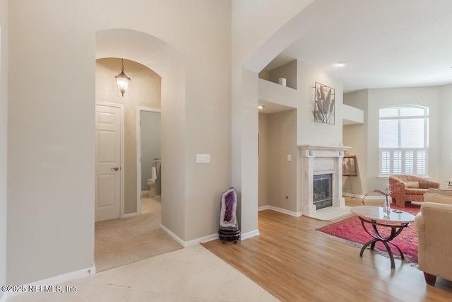 living room with baseboards, arched walkways, wood finished floors, and a fireplace