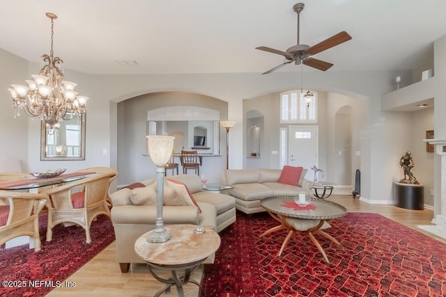 living area with ceiling fan, baseboards, arched walkways, and wood finished floors