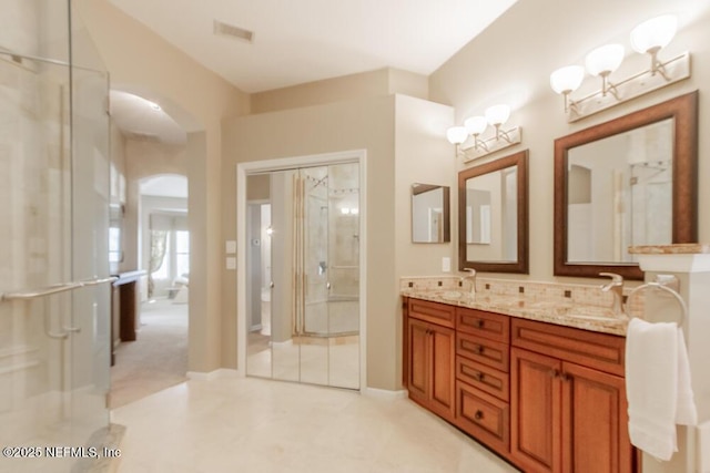 full bathroom featuring a sink, visible vents, a shower with shower door, and double vanity