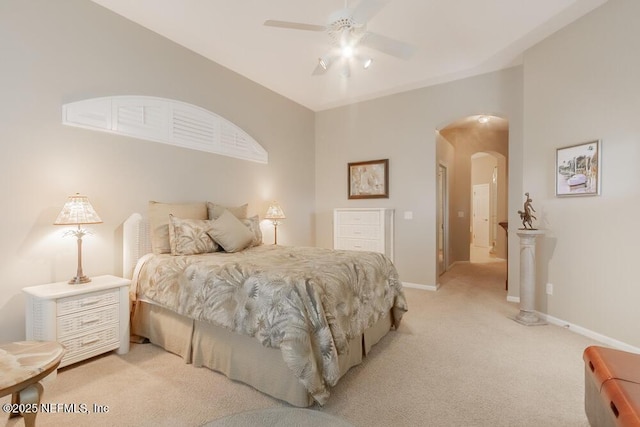 bedroom with baseboards, arched walkways, light colored carpet, and ceiling fan