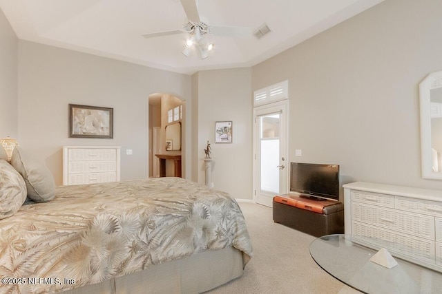 carpeted bedroom featuring visible vents, arched walkways, and ceiling fan