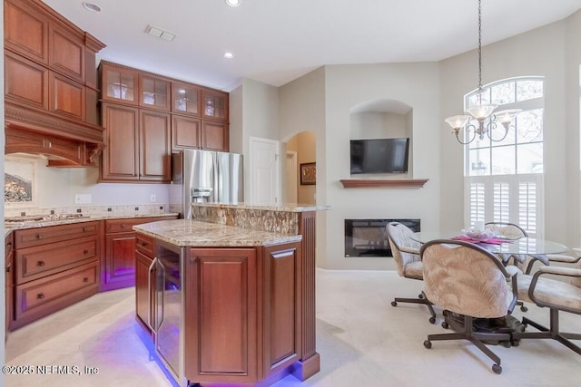 kitchen with visible vents, a kitchen island, hanging light fixtures, a glass covered fireplace, and stainless steel appliances