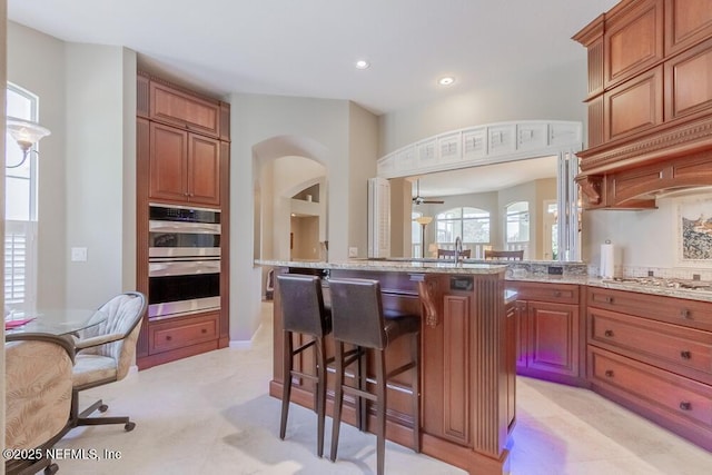 kitchen with plenty of natural light, appliances with stainless steel finishes, a breakfast bar, and light stone countertops