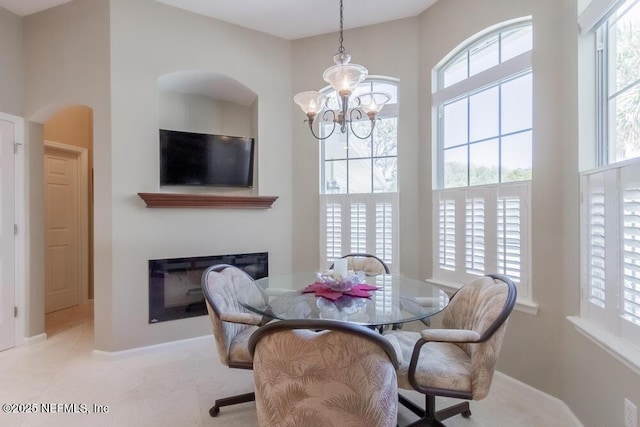 dining room with a chandelier, a high ceiling, and a glass covered fireplace