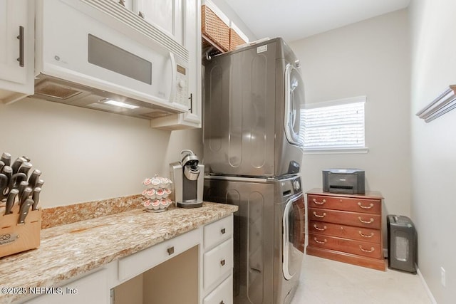 clothes washing area featuring stacked washer and dryer and cabinet space