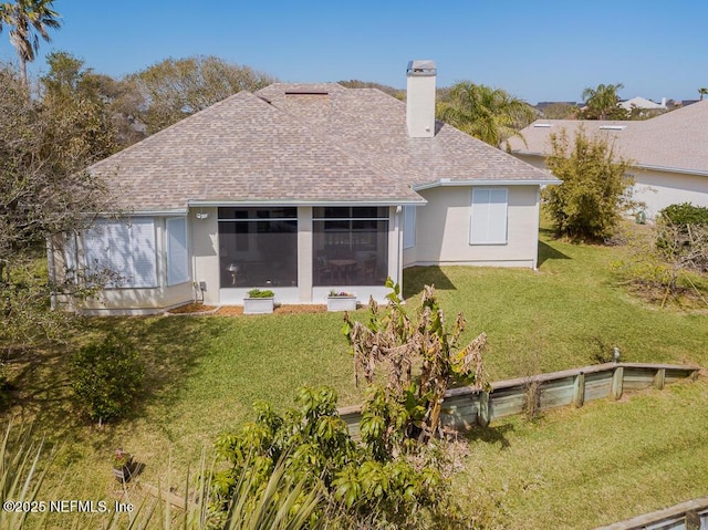 rear view of house with a shingled roof, stucco siding, a chimney, a yard, and a sunroom