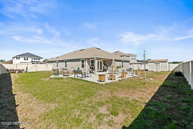 back of property with a patio, a lawn, a fenced backyard, and an outdoor structure