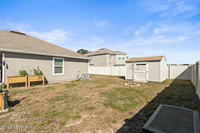 view of yard with a storage unit, an outbuilding, central AC unit, and a fenced backyard