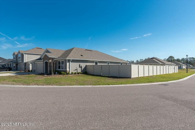 view of property exterior featuring fence, a lawn, and a residential view