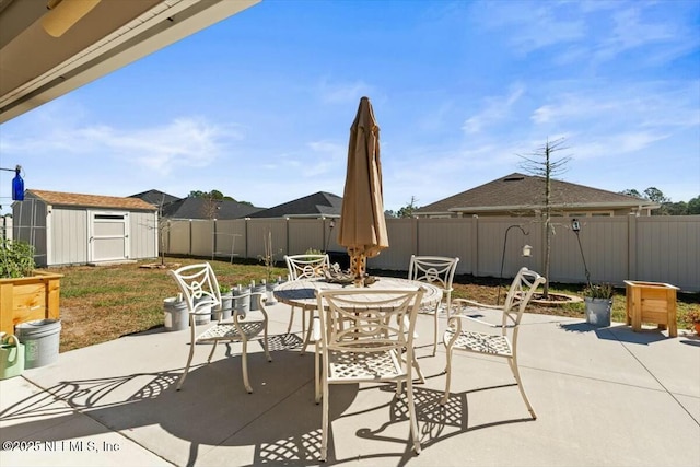 view of patio / terrace featuring a fenced backyard, a storage shed, outdoor dining space, and an outdoor structure