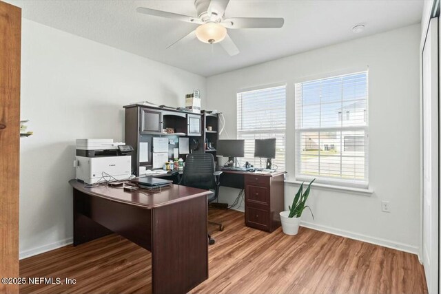 office space with baseboards, light wood-type flooring, and a ceiling fan