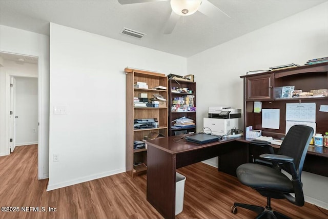 office space with ceiling fan, visible vents, baseboards, and wood finished floors