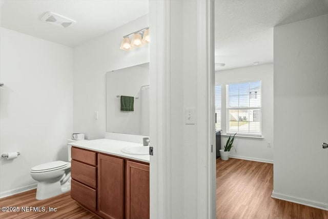 bathroom with visible vents, toilet, wood finished floors, baseboards, and vanity