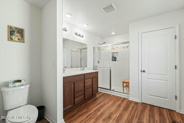 full bathroom featuring wood finished floors, visible vents, a sink, a shower stall, and toilet