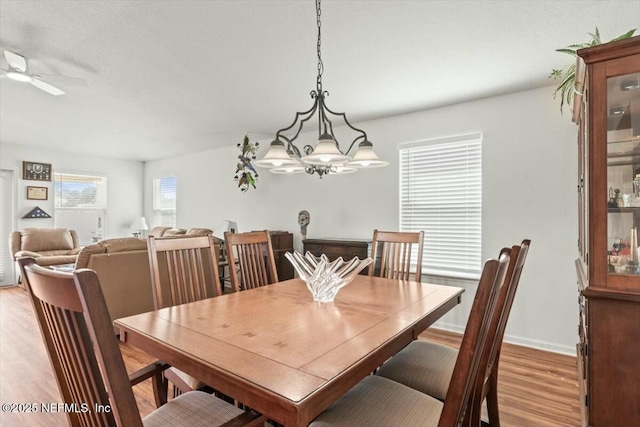 dining space with a ceiling fan, light wood-type flooring, and baseboards