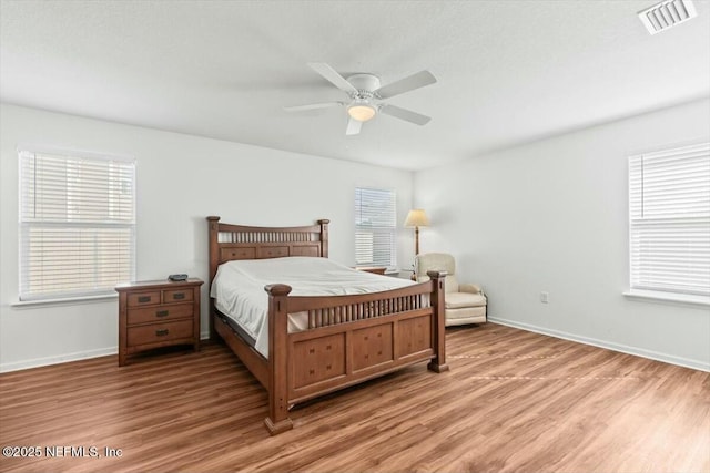 bedroom featuring baseboards, visible vents, light wood finished floors, and ceiling fan