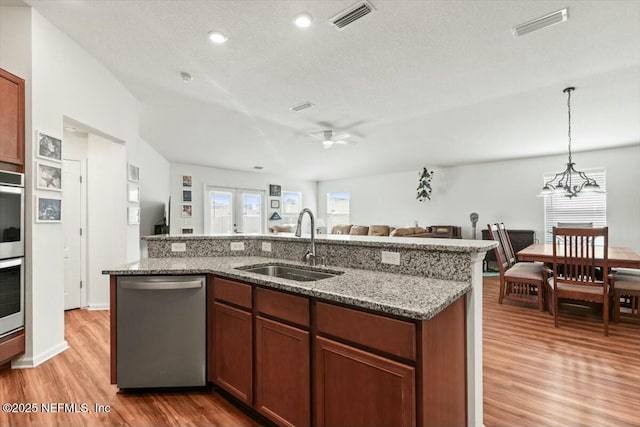 kitchen with a sink, light wood-style flooring, open floor plan, and stainless steel appliances