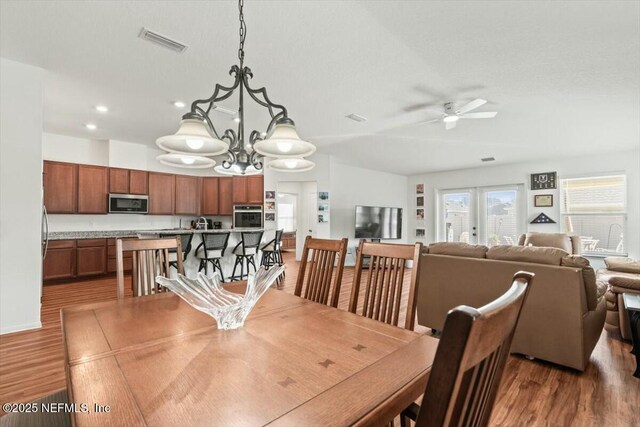 dining room featuring visible vents, ceiling fan with notable chandelier, french doors, and wood finished floors