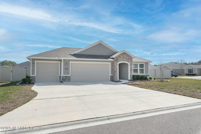 view of front of property featuring fence, concrete driveway, a garage, stone siding, and a gate