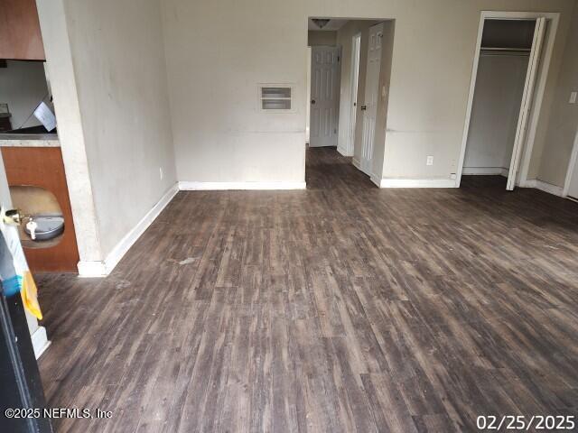 unfurnished bedroom featuring dark wood-style floors, visible vents, a closet, and baseboards