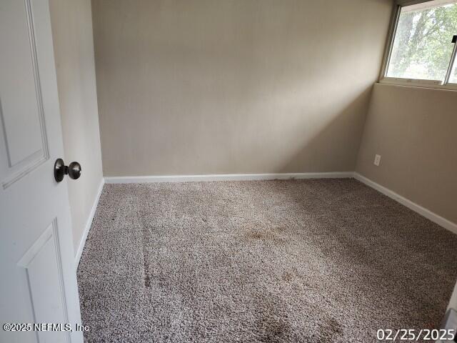 unfurnished room with carpet flooring and baseboards