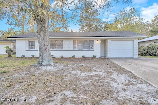 single story home featuring brick siding, an attached garage, concrete driveway, and a shingled roof