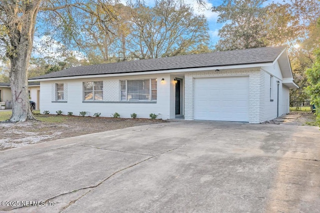 ranch-style house with brick siding, concrete driveway, an attached garage, and a shingled roof