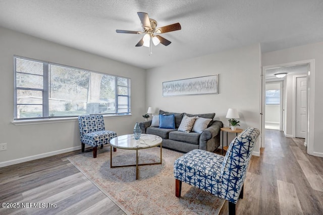 living room with a healthy amount of sunlight, a textured ceiling, baseboards, and wood finished floors