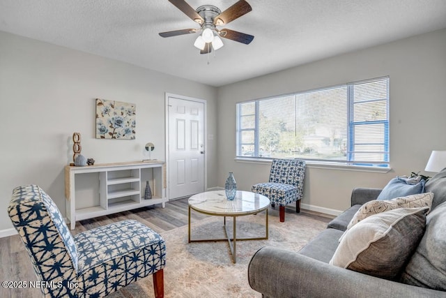 living room with baseboards, a textured ceiling, wood finished floors, and a ceiling fan