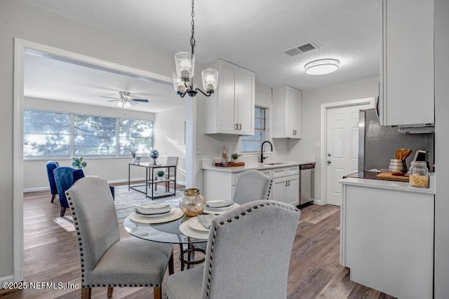 dining area with visible vents, baseboards, ceiling fan, wood finished floors, and a textured ceiling