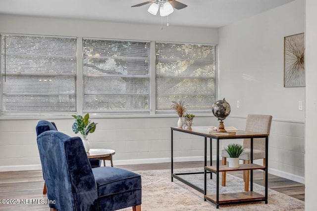 living area with a ceiling fan, wood finished floors, and baseboards