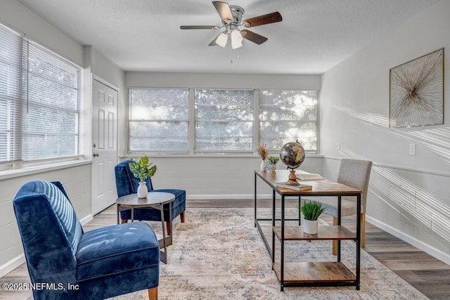 interior space featuring ceiling fan, baseboards, a textured ceiling, and wood finished floors