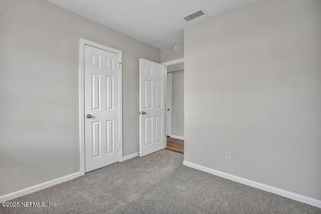 unfurnished bedroom featuring visible vents, baseboards, and carpet