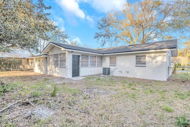 rear view of property featuring central air condition unit, a yard, and fence