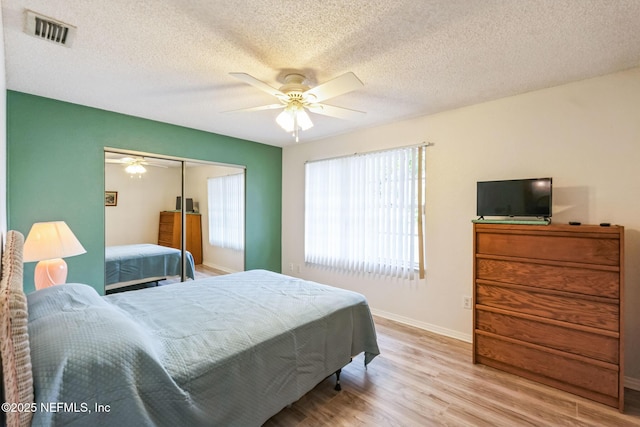 bedroom featuring visible vents, wood finished floors, a closet, baseboards, and ceiling fan